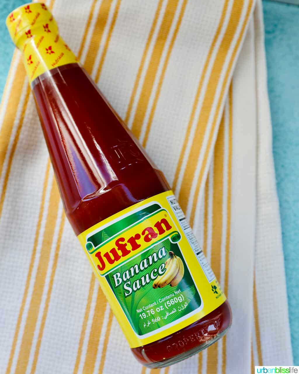 bottle of Filipino banana ketchup on a white and yellow striped towel.