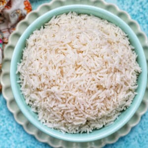 white basmati rice in a blue bowl on green plate.