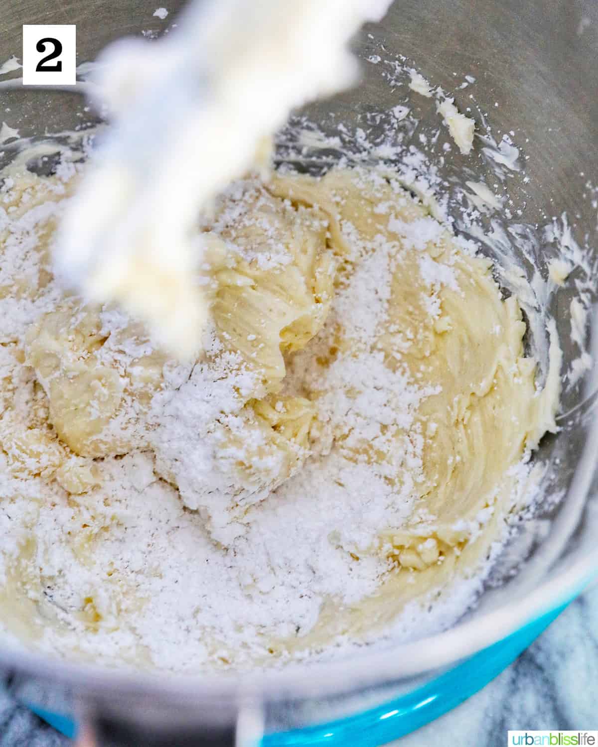 adding powdered sugar to butter to make buttercream frosting.