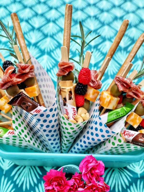 Charcuterie cones with fruit, cheeses, breadsticks, nuts, chocolate, herbs in paper cones.