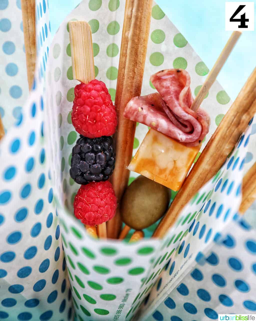 Charcuterie cones with fruit, cheeses, breadsticks, nuts, chocolate, herbs in paper cones.