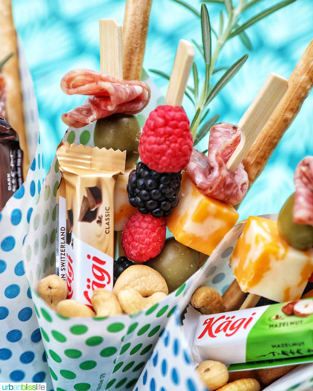 Charcuterie cones with fruit, cheeses, breadsticks, nuts, chocolate, herbs in paper cones.