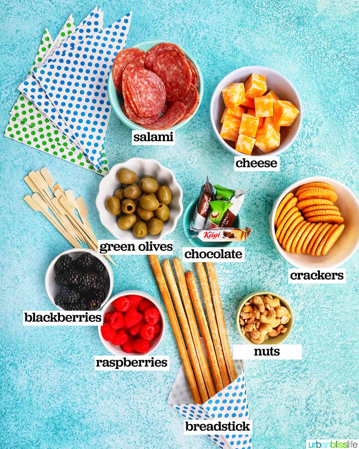 bowls of ingredients on a blue background to make charcuterie cones.