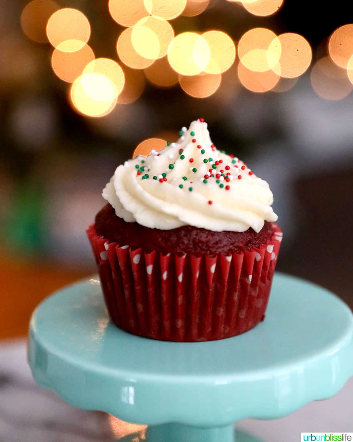 vanilla buttercream frosting on a red velvet cupcake with bokeh twinkle lights in the background.