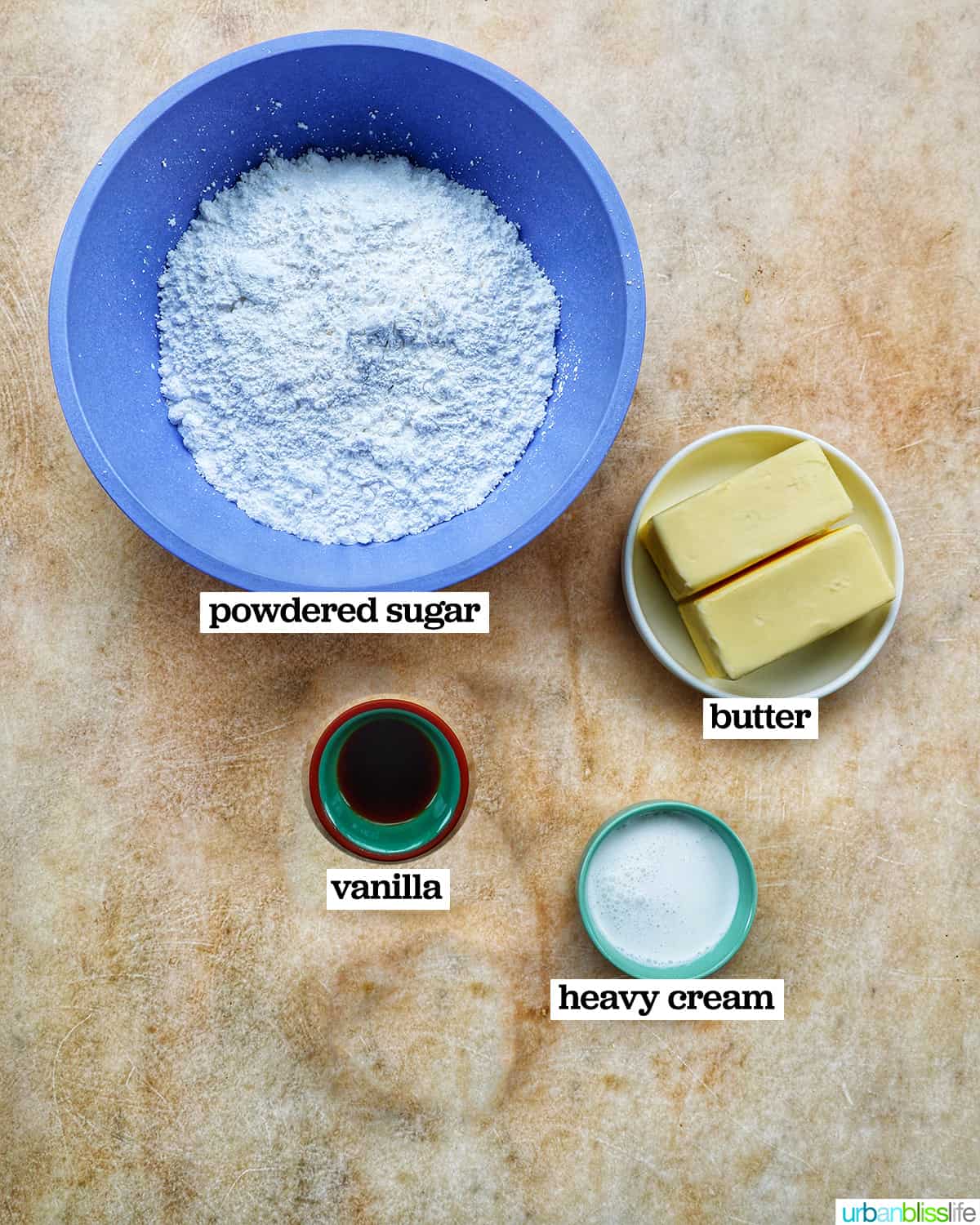 ingredients to make vanilla buttercream frosting: powdered sugar, butter, vanilla, and cream.