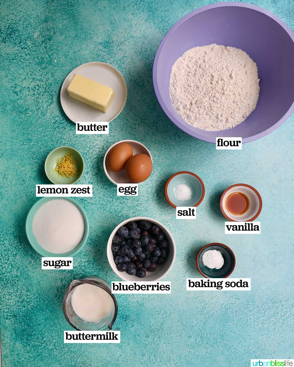 bowls of ingredients to make lemon blueberry pound cake on a blue background.