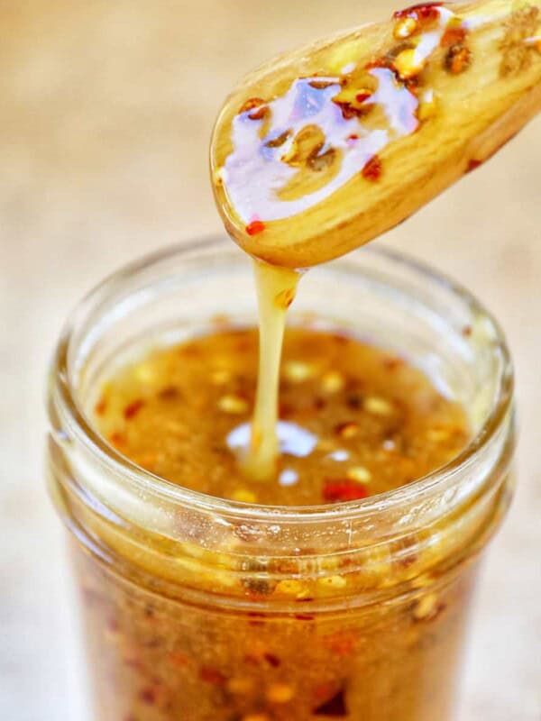 honey spoon lifting hot honey sauce out of a mason jar.