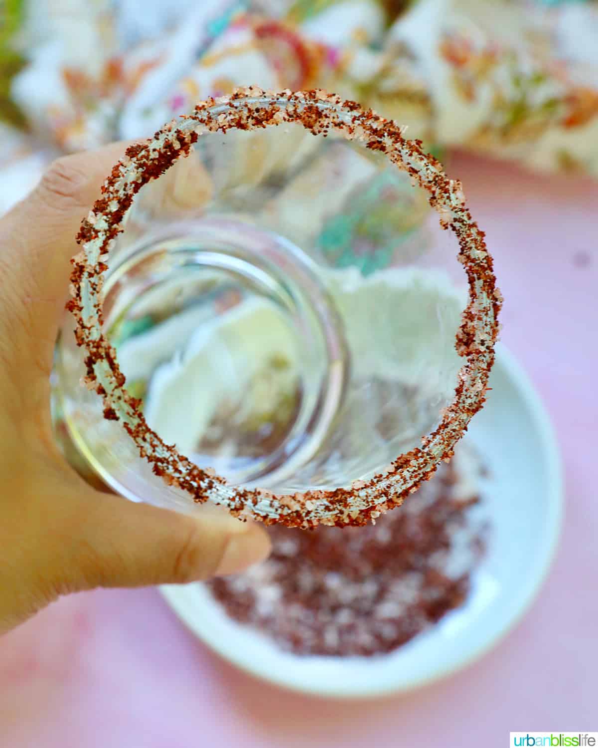 hand holding a glass with chili powder salt around the rim.