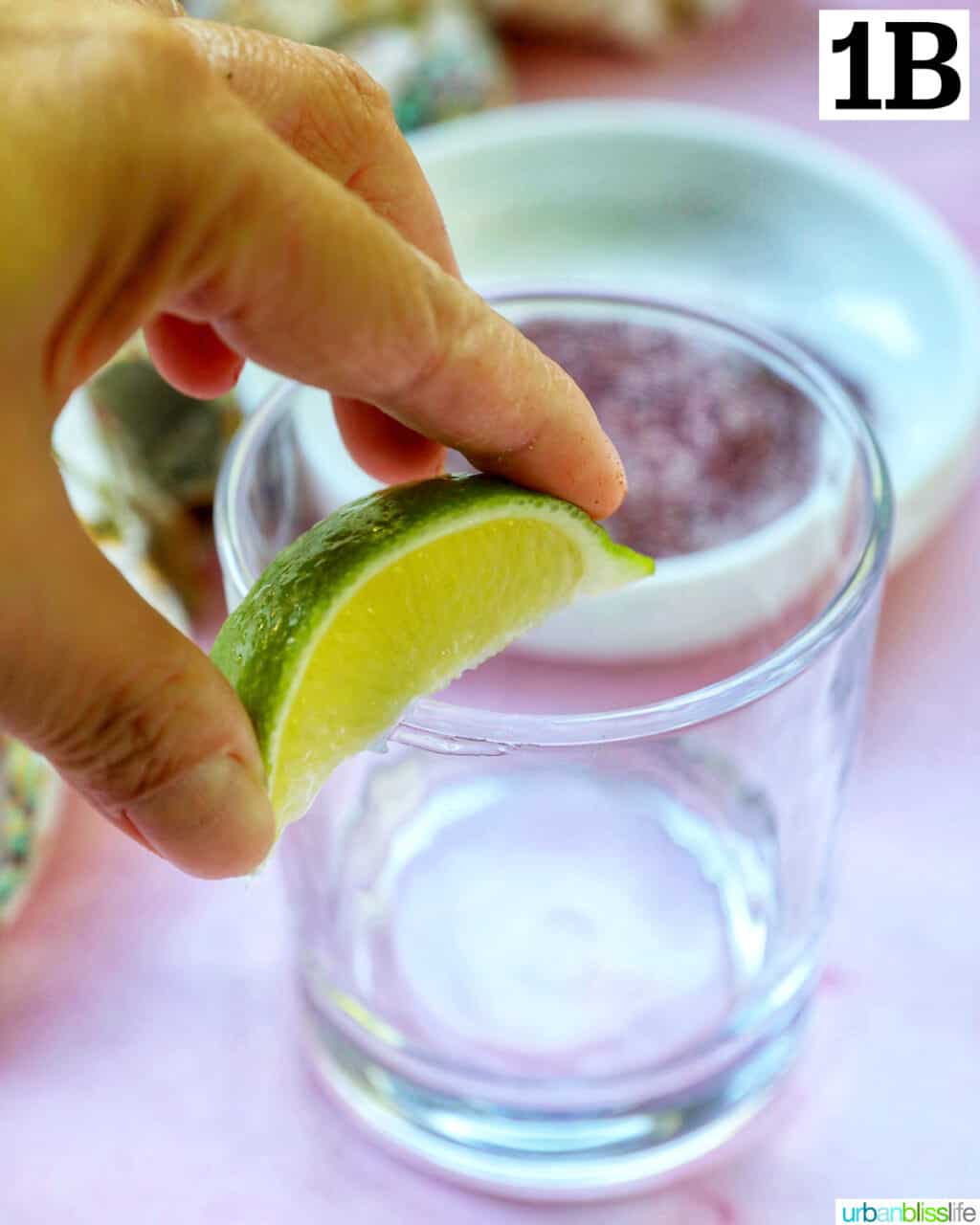 hand running a lime wedge around the rim of a glass for margaritas.
