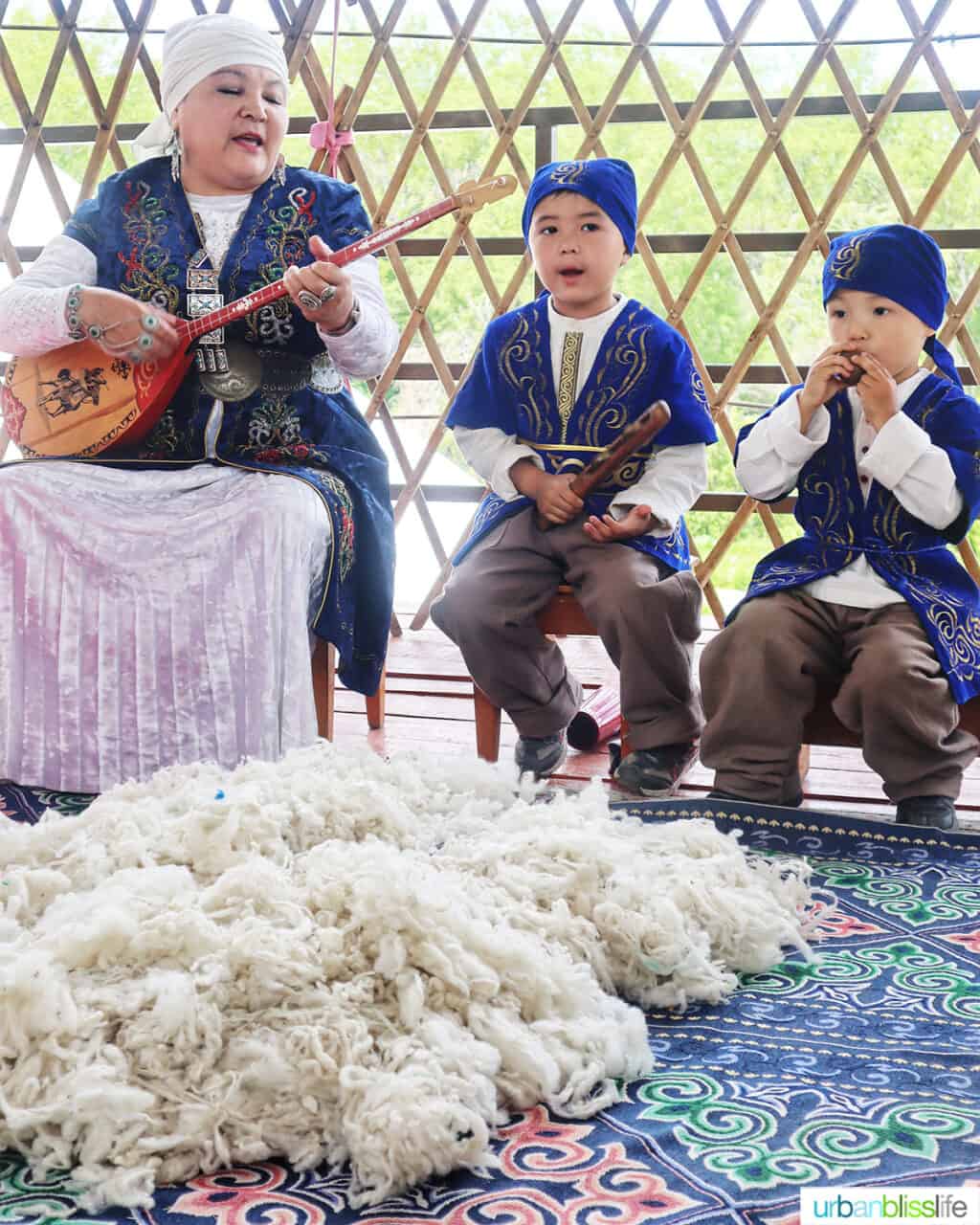 Woman with two children playing musical instruments at Ethno Village of the Huns near Almaty, Kazakhstan.