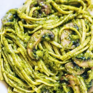 closeup of linguine pasta in pesto sauce with chopped mushrooms.