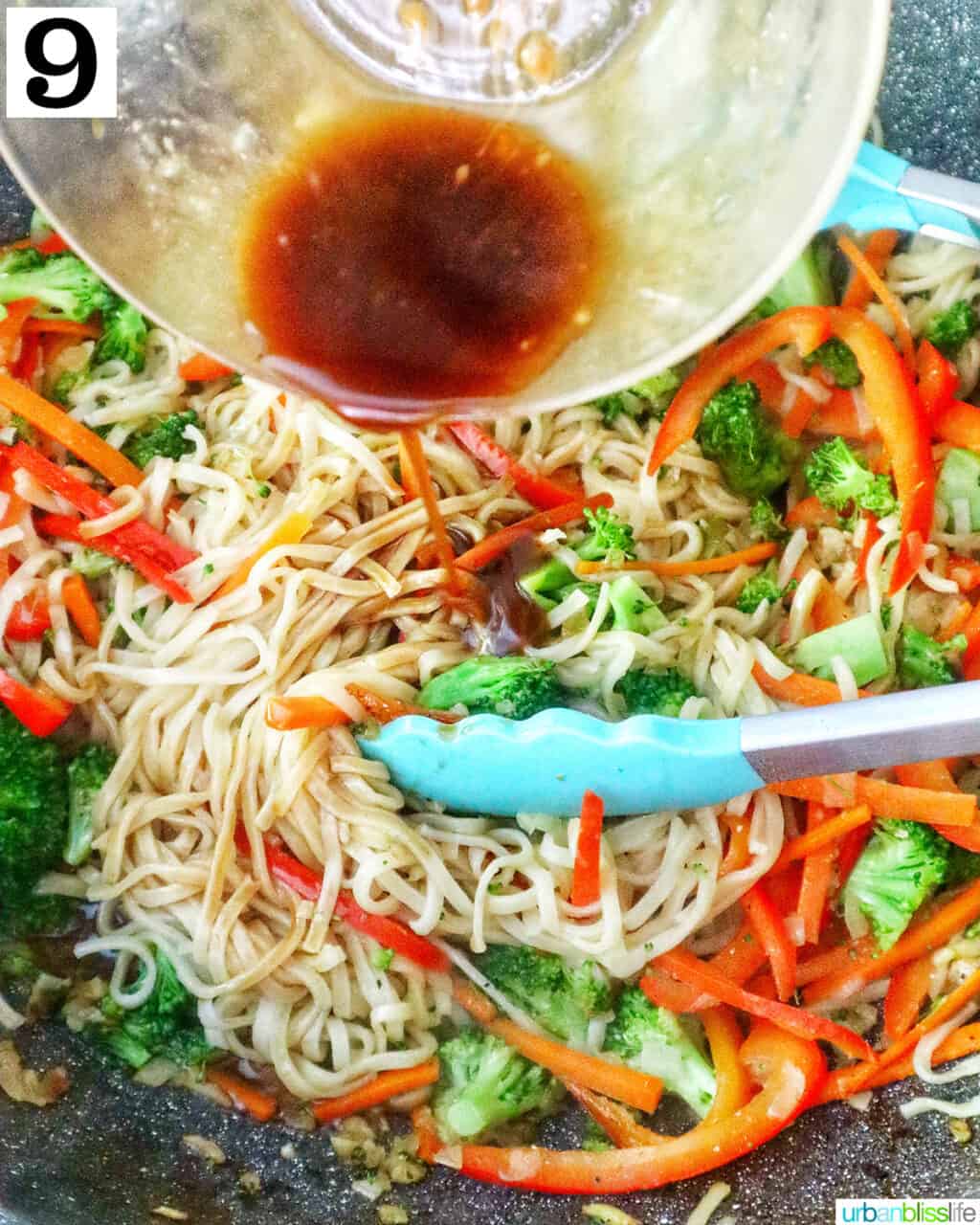 bowl of soy sauce over a wok of prawn chow mein noodles.