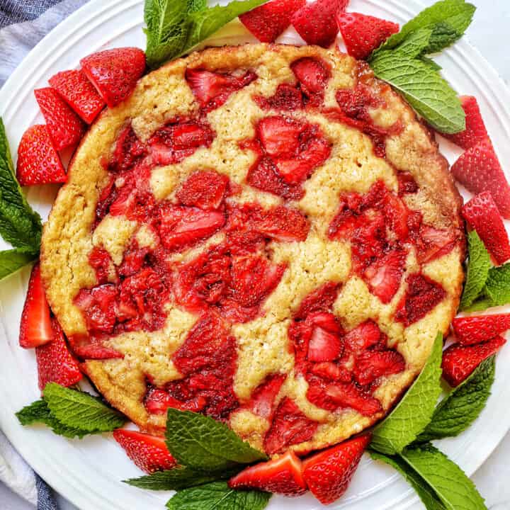 Strawberry Spoon Cake with mint leaves and sliced strawberries as garnish on a white plate.
