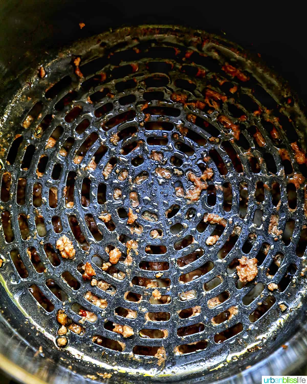 ground beef drained at the bottom of an air fryer.