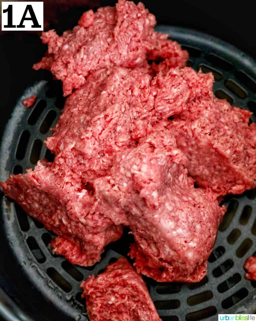 ground beef in an air fryer basket.