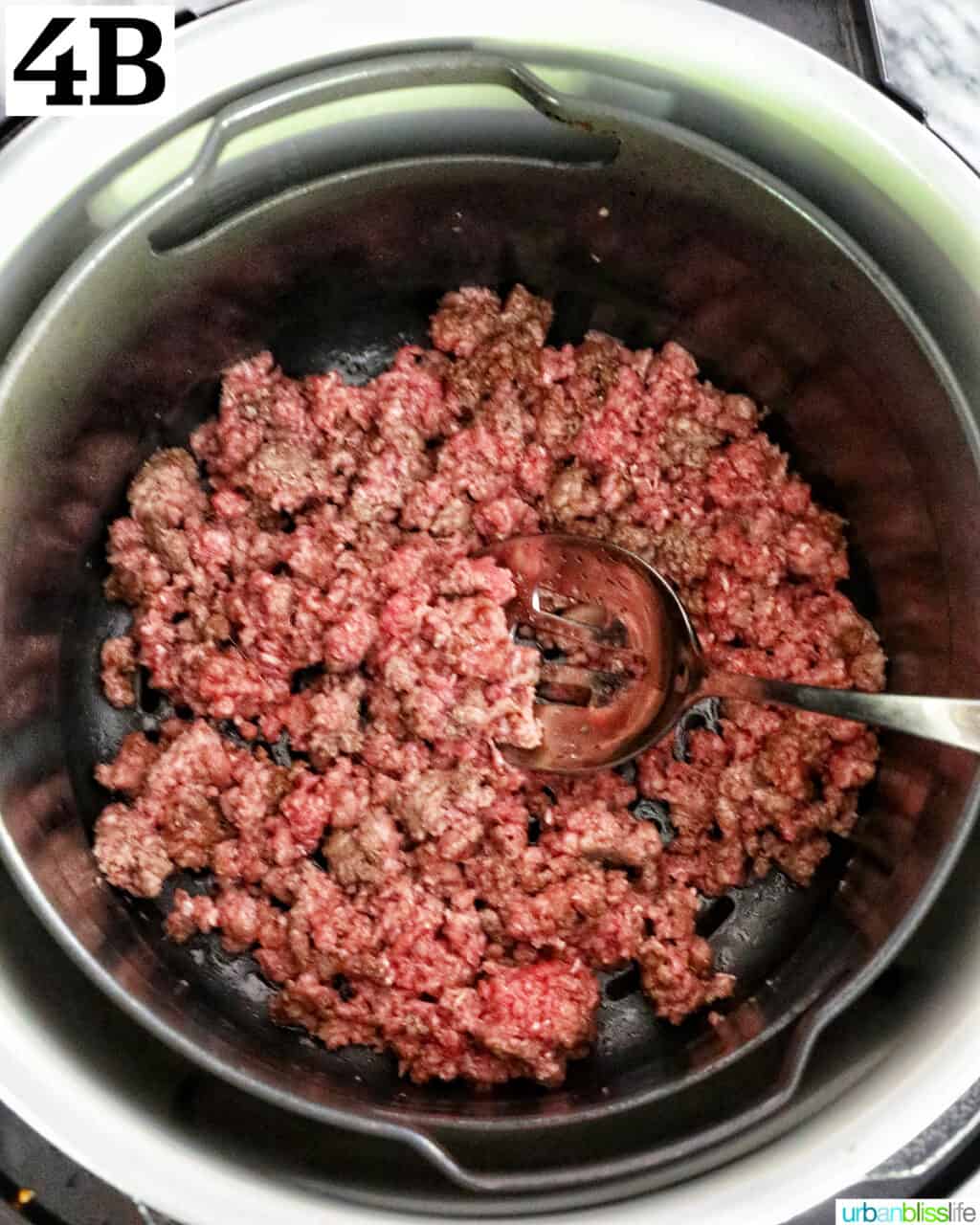 ground beef cooking in an air fryer basket.