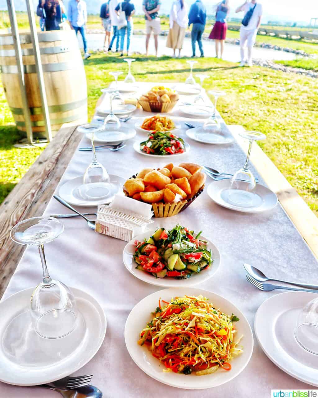 table set with several dishes for a vineyard dinner and people in the background at Arba Winery near Almaty, Kazakhstan.