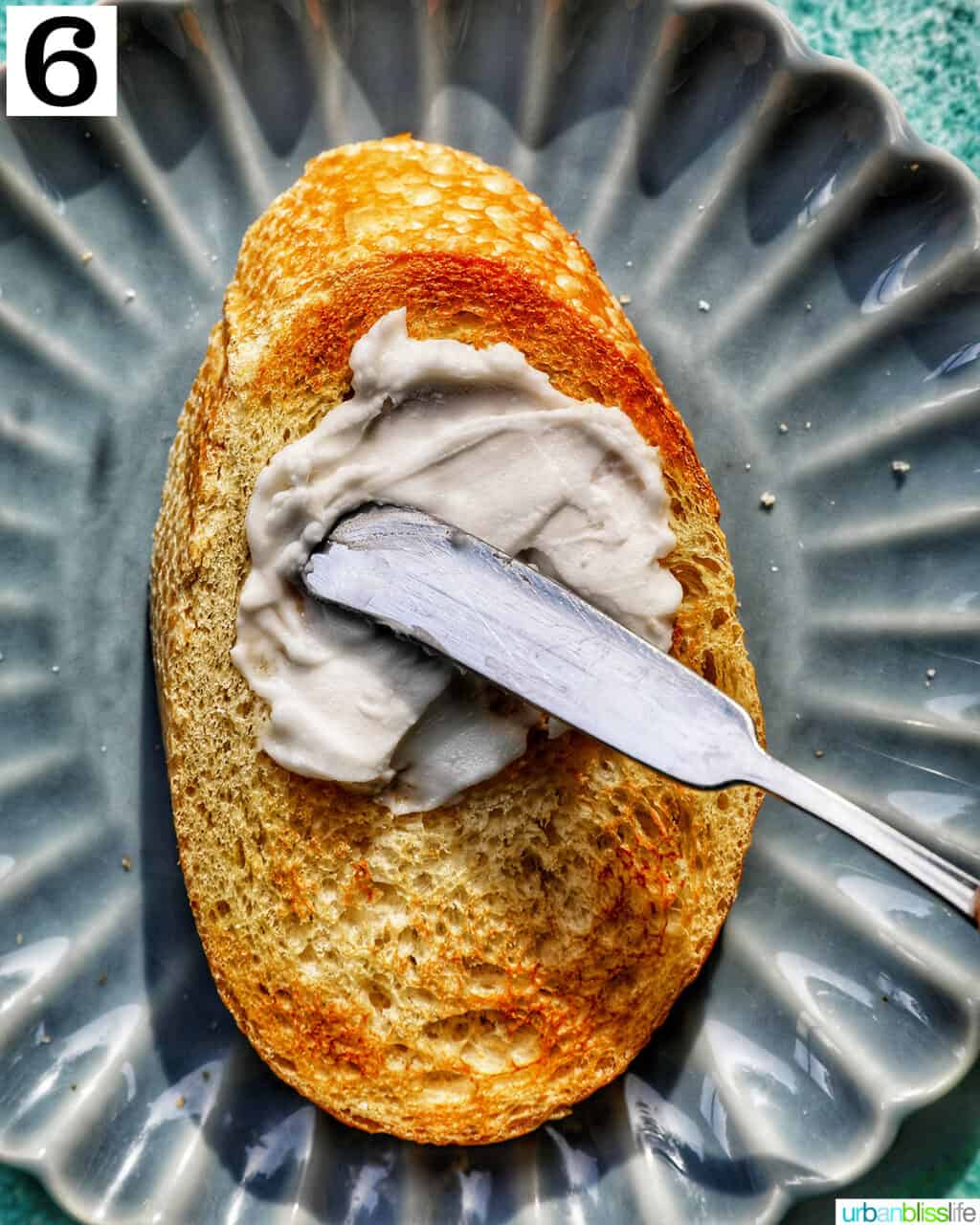 spreading cream cheese on a blue plate.
