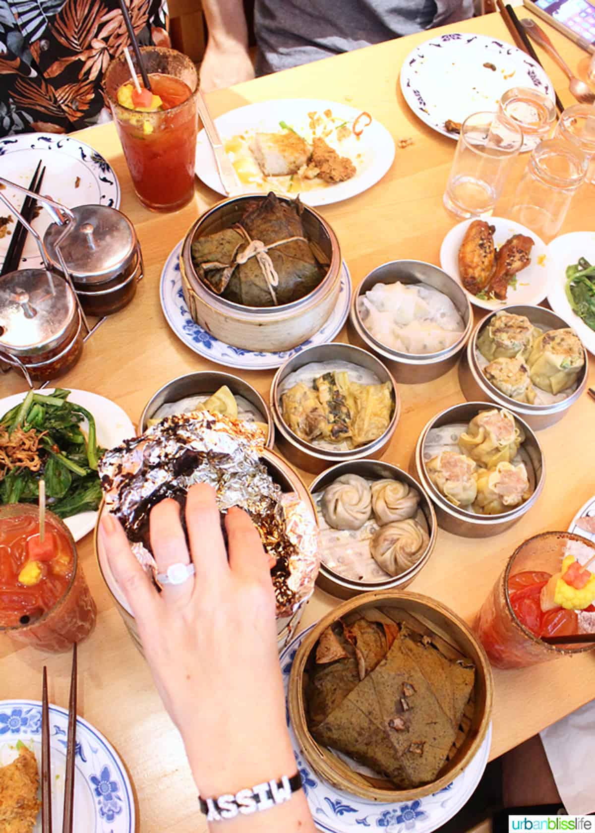 hand reaching for food from a table full of dim sum dumplings at Boke Bowl in Portland, Oregon.