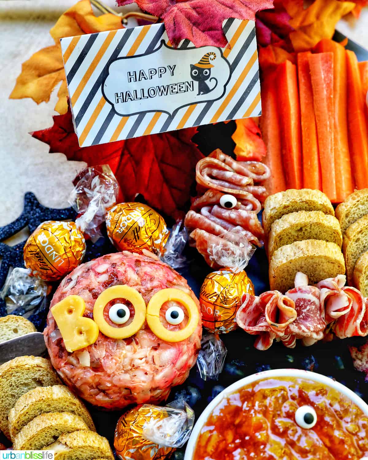 Halloween Charcuterie Board with charcuterie meats, cheeses, crackers, jams, pretzels, fruits, candy eyes, and more orange, purple, and black food.