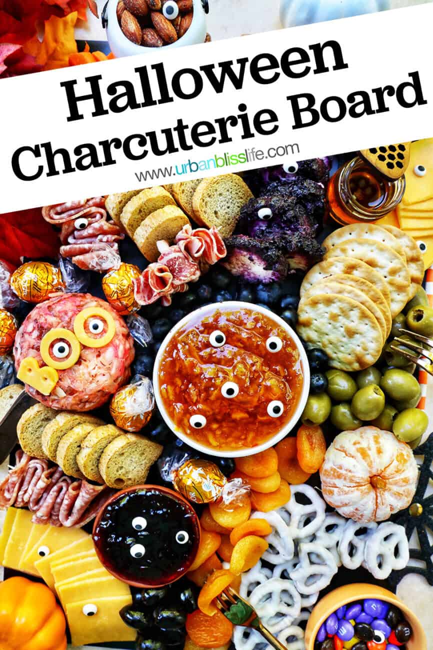 Halloween Charcuterie Board with charcuterie meats, cheeses, crackers, jams, pretzels, fruits, candy eyes, and more orange, purple, and black food.
