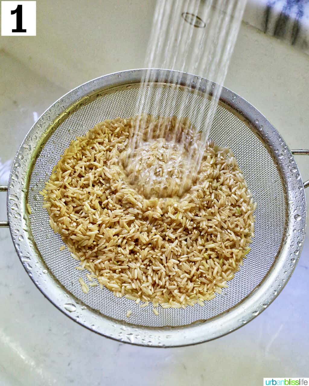 rinsing brown rice in a strainer over the sink.