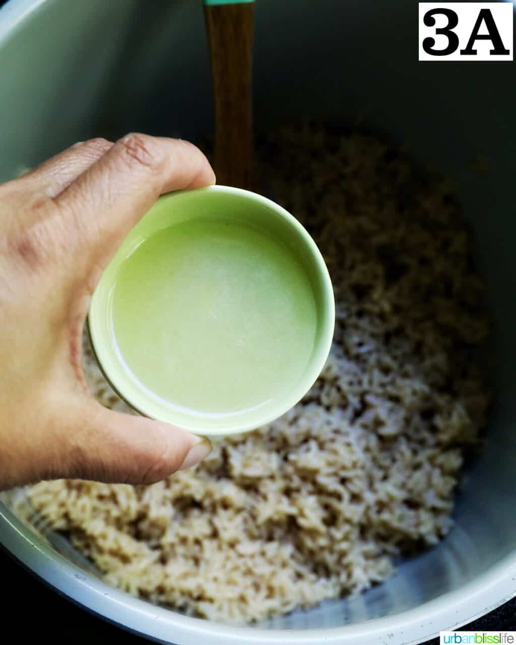 hand holding a bowl of lime juice over brown rice in an instant pot.