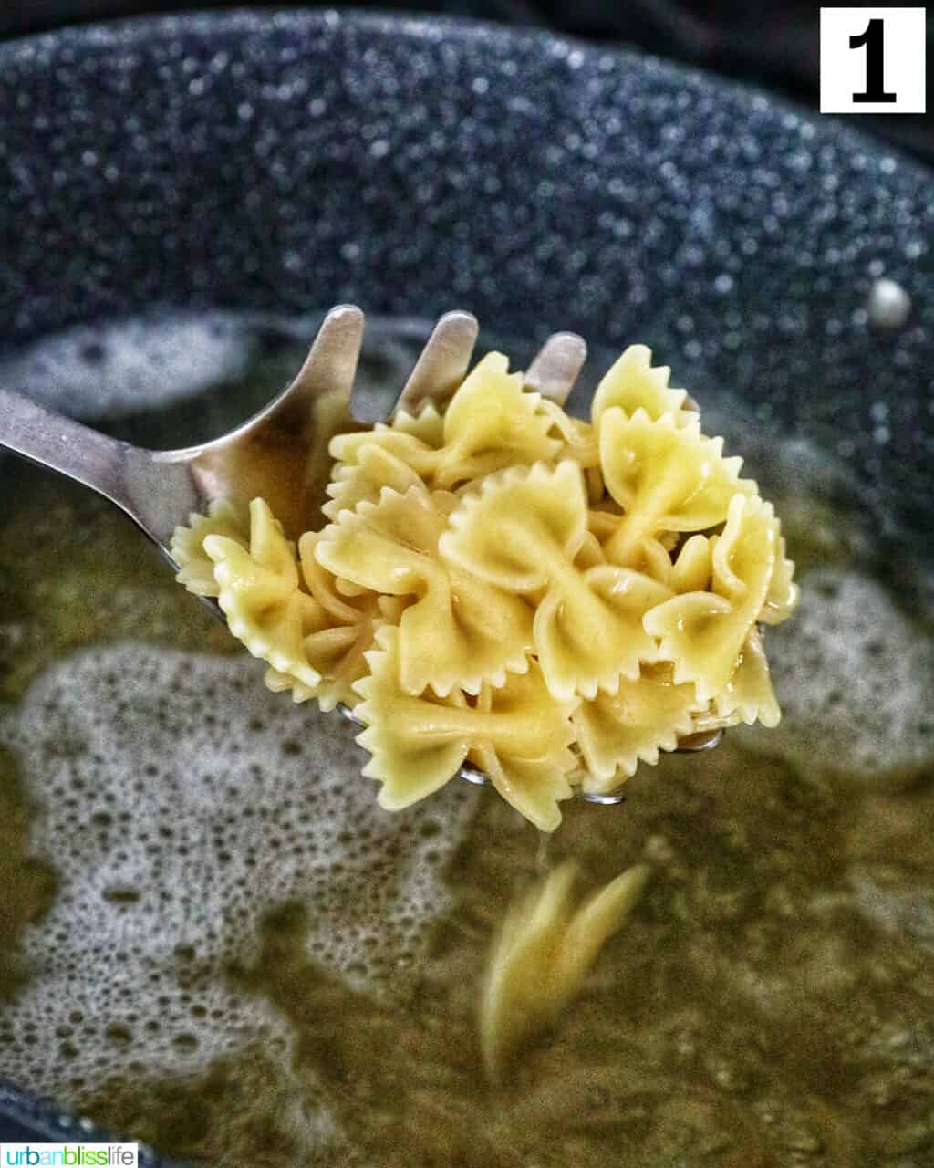 slotted spoon holding up bowtie pasta over a large pot of pasta cooking.