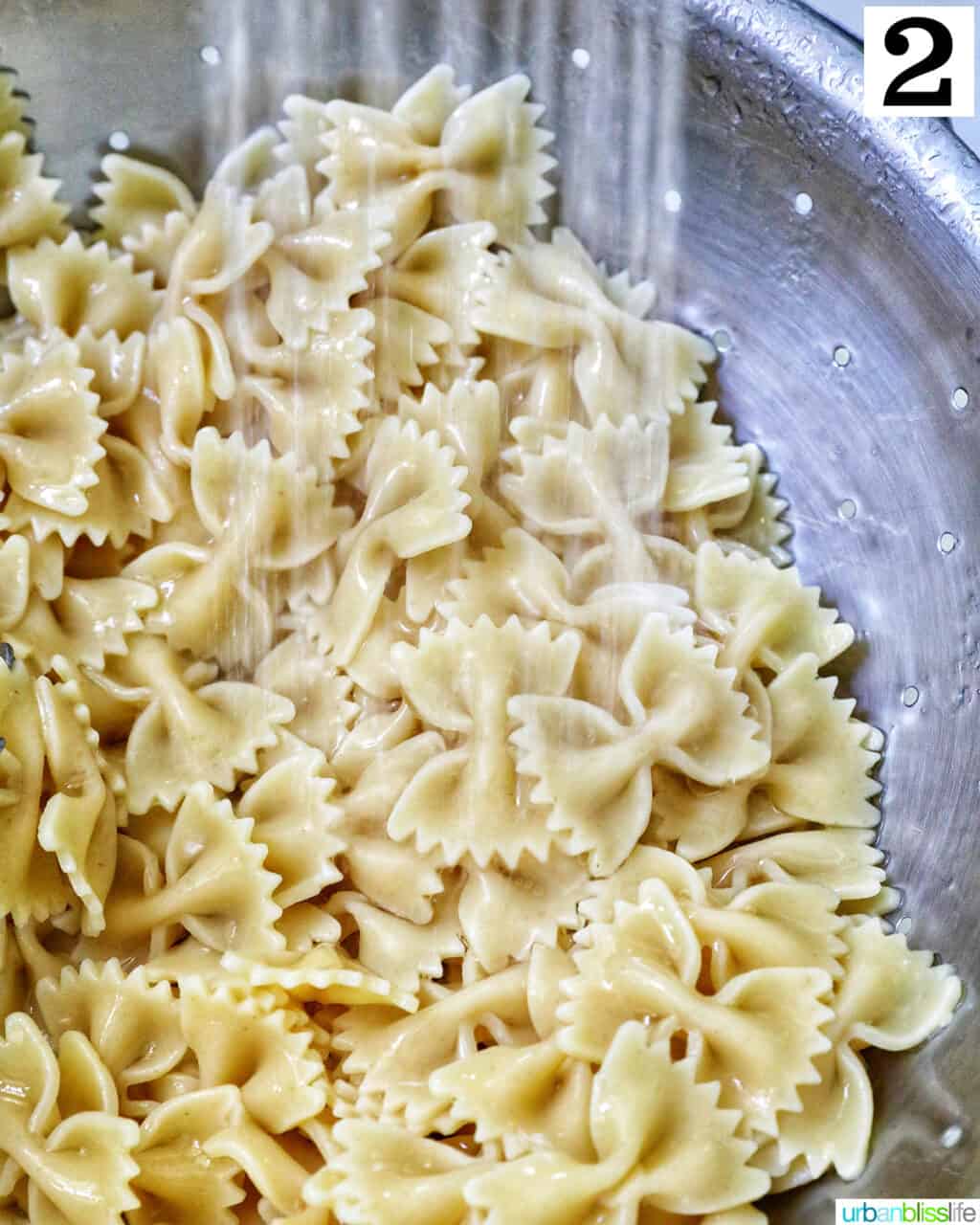 water rinsing off bowtie pasta in a collander.