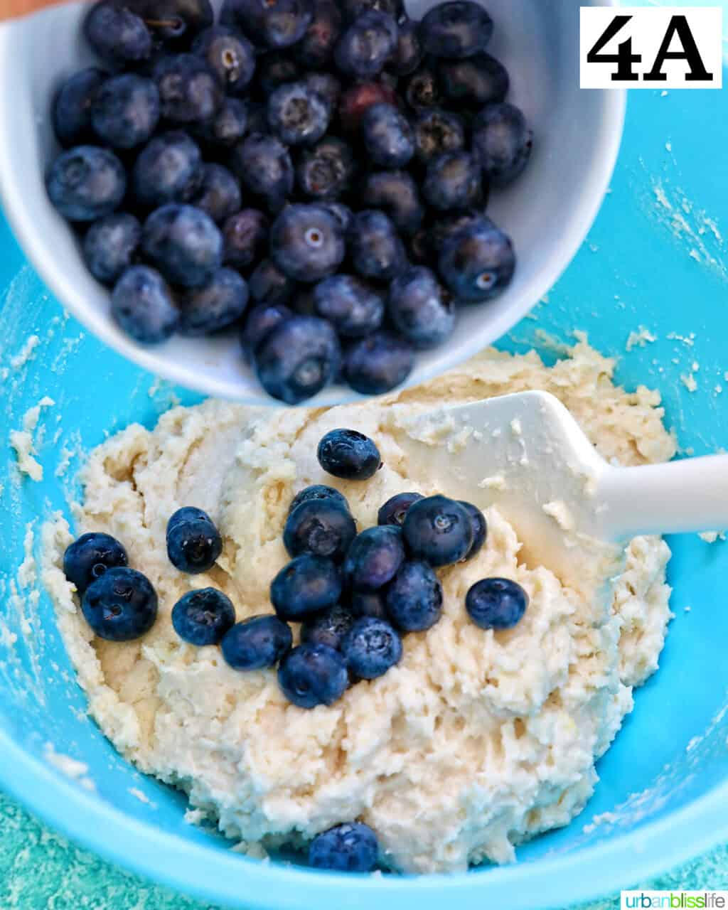 pouring blueberries into dry batter ingredients to make lemon blueberry cookies.