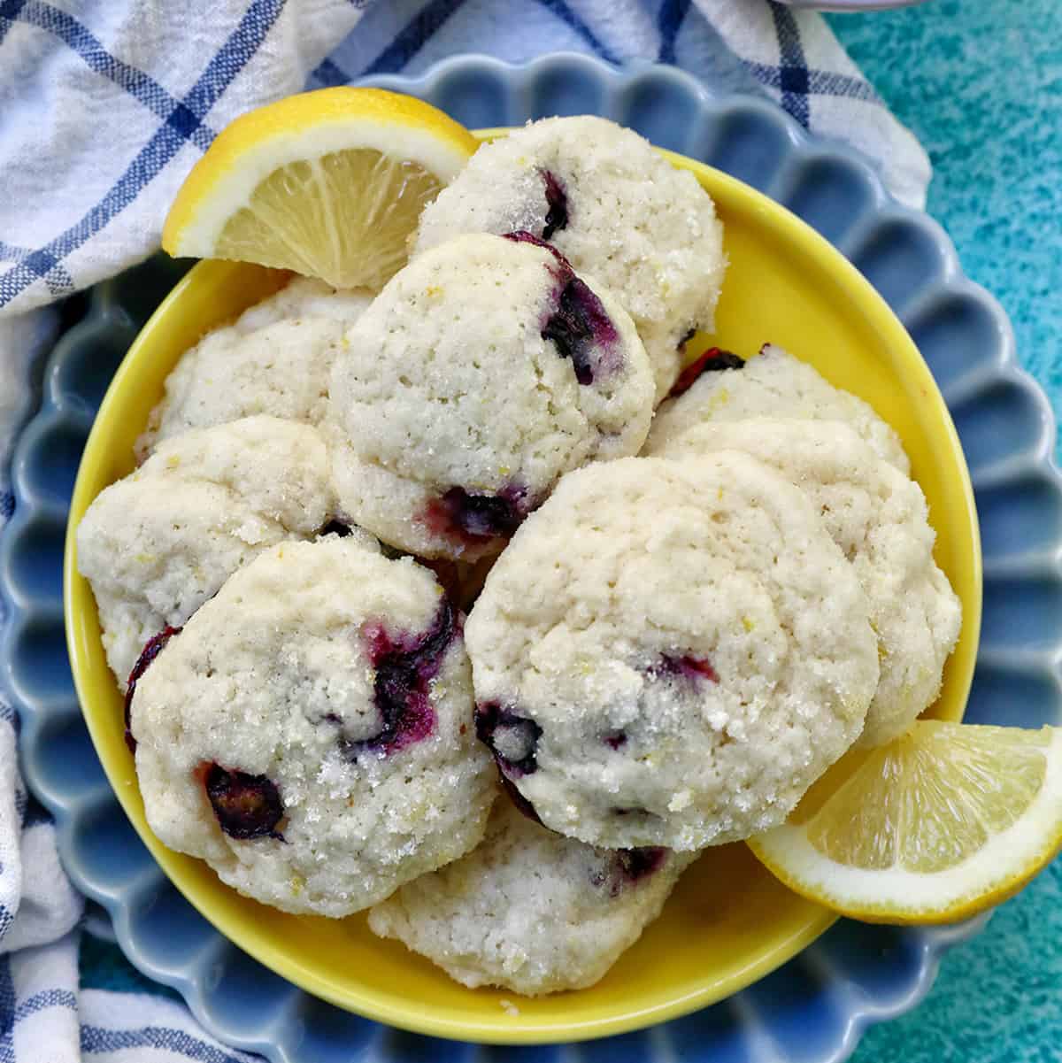 lemon blueberry cookies on a yellow and blue plate with lemon slices.