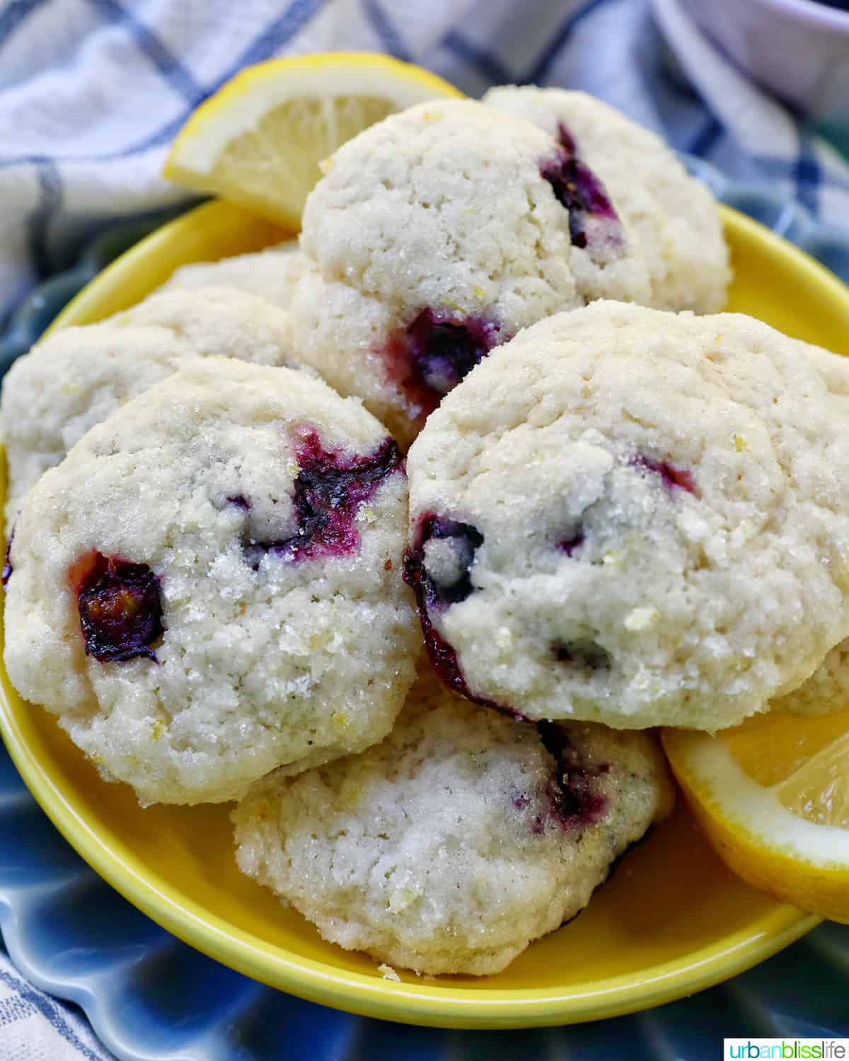 lemon blueberry cookies on a yellow and blue plate with lemon slices.