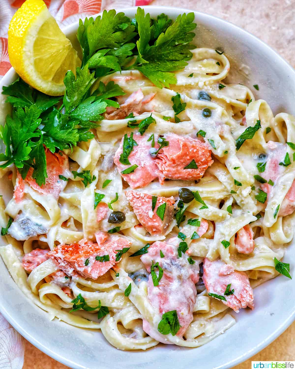 Pasta Alla Salmone with garnishes of lemon and parsley in a white bowl.