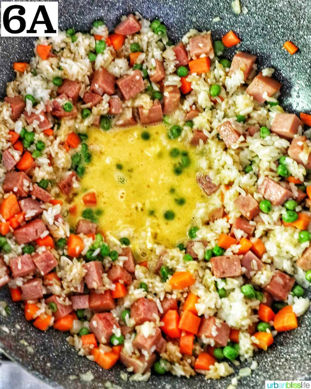 egg in the middle for spam fried rice in a wok.