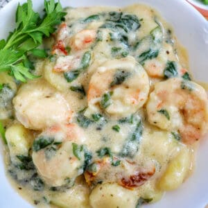 Tuscan Shrimp Gnocchi in a white bowl with garnish of parsley leaves.
