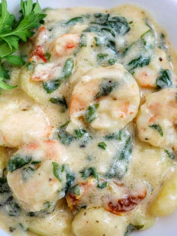 Tuscan Shrimp Gnocchi in a white bowl with garnish of parsley leaves.