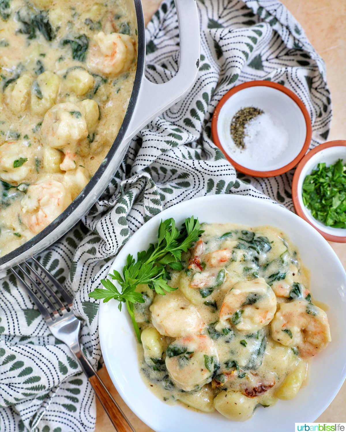 Tuscan Shrimp Gnocchi in a white bowl with garnish of parsley leaves.