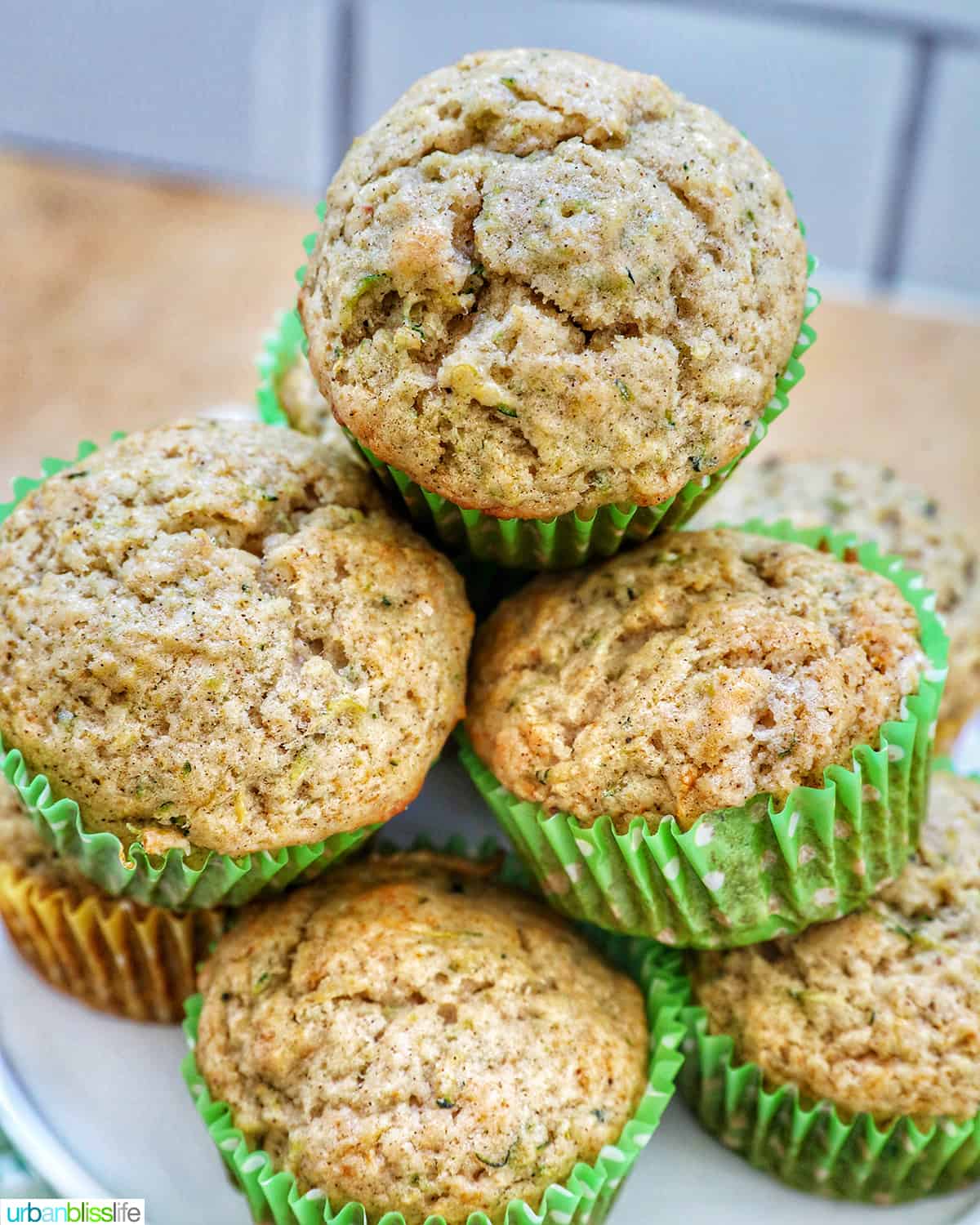 vegan zucchini muffins stacked on top of each other on a white plate.