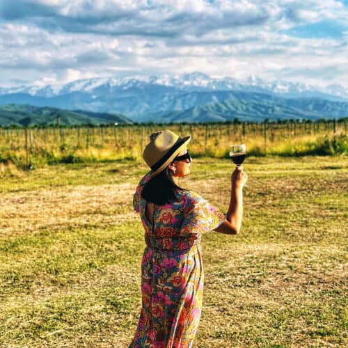 Marlynn Jayme Schotland holding a glass of Kazakhstan wine at Arba Winery with the Tian Shan mountains in the background.