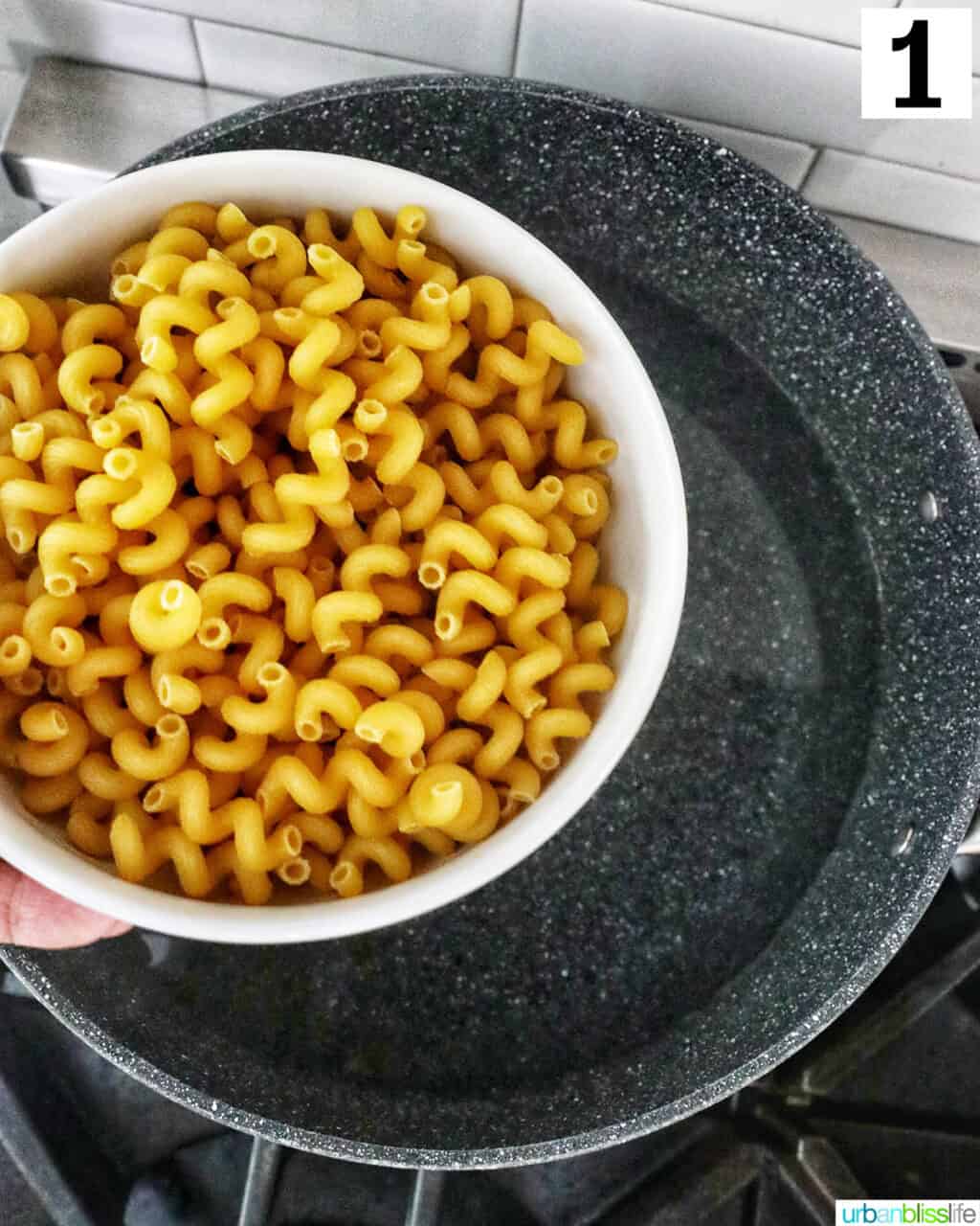 cellentani corkscrew pasta in a white bowl over a large pot of water.