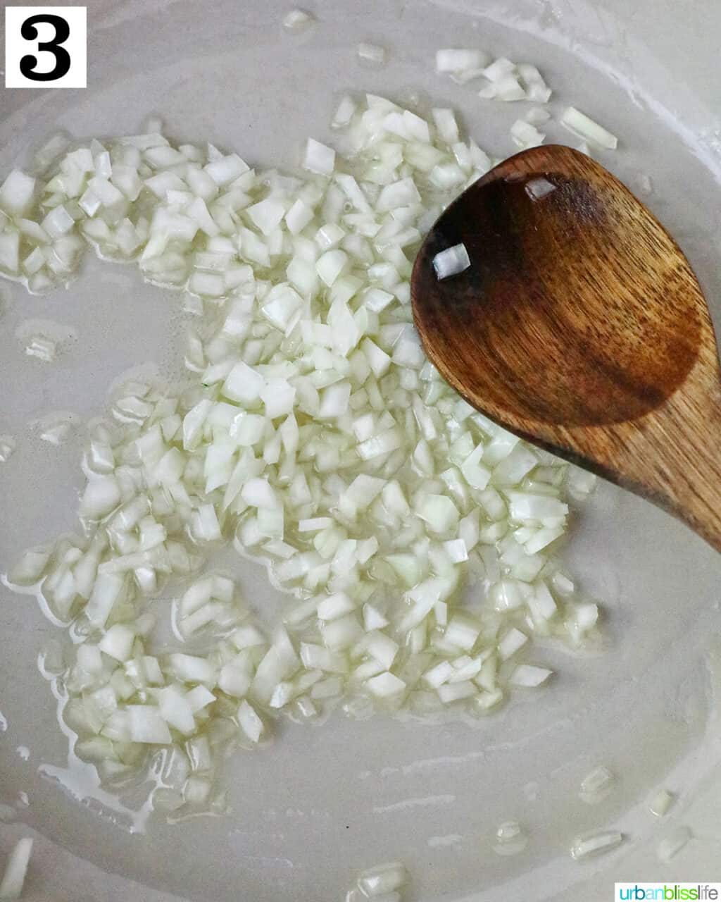 a pan with onions, olive oil, and a wooden spoon.