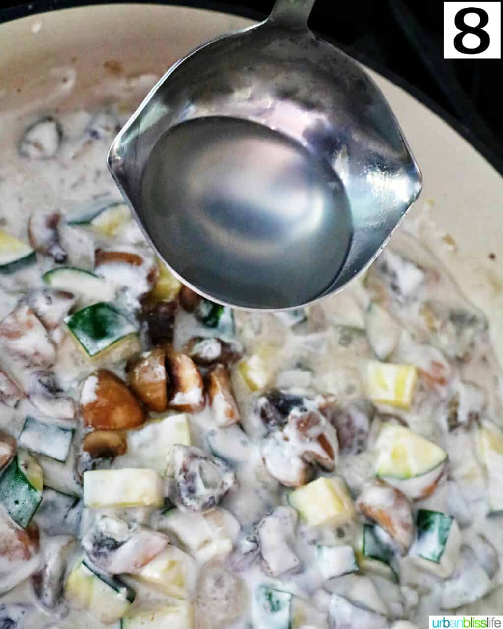 ladle of starchy pasta water over a saucepan with mushrooms and zucchini.