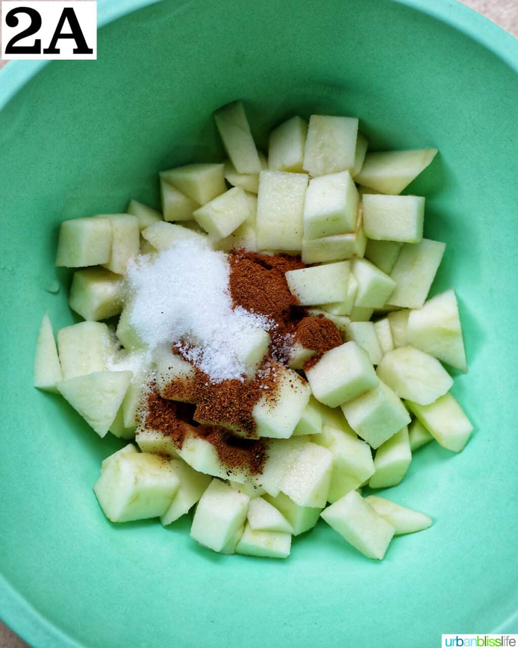 green bowl with diced apples and spices.