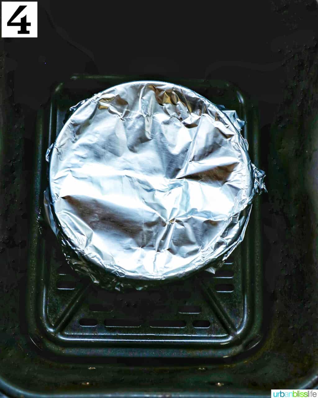 bowl wrapped in aluminum foil in an air fryer basket.