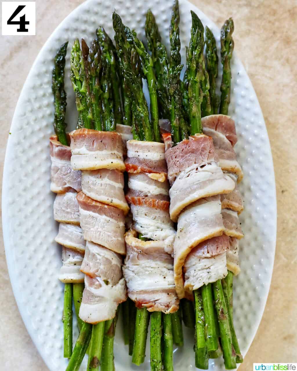 bacon wrapped asparagus on a white plate.