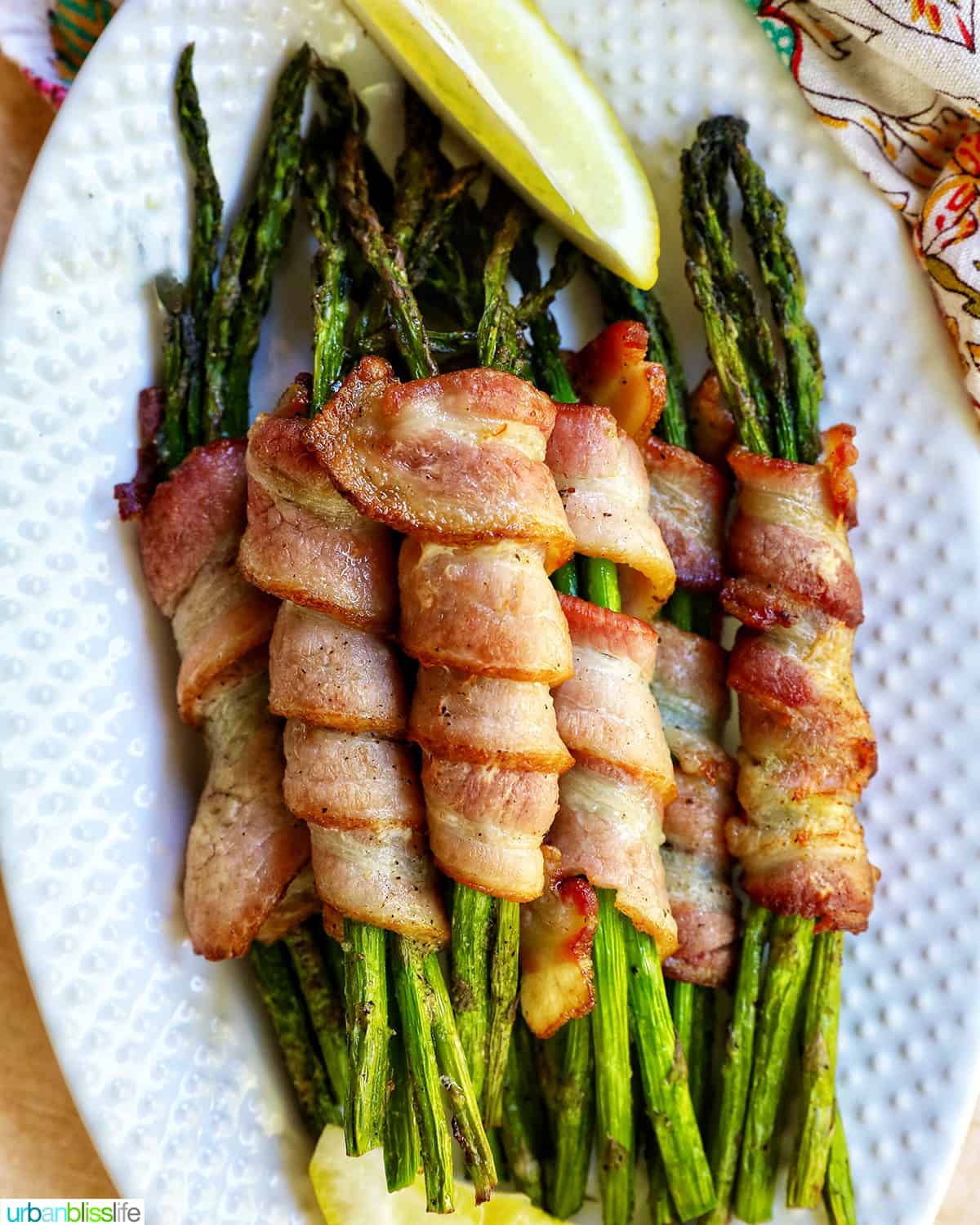 bacon wrapped asparagus on a white plate.