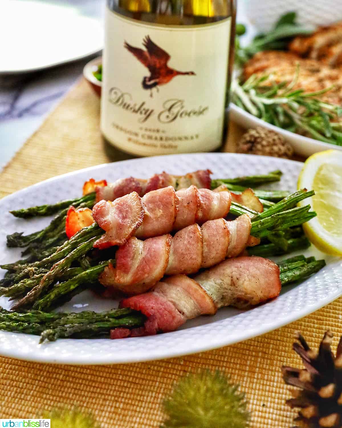 bacon wrapped asparagus on a white plate with a bottle of Oregon Chardonnay.