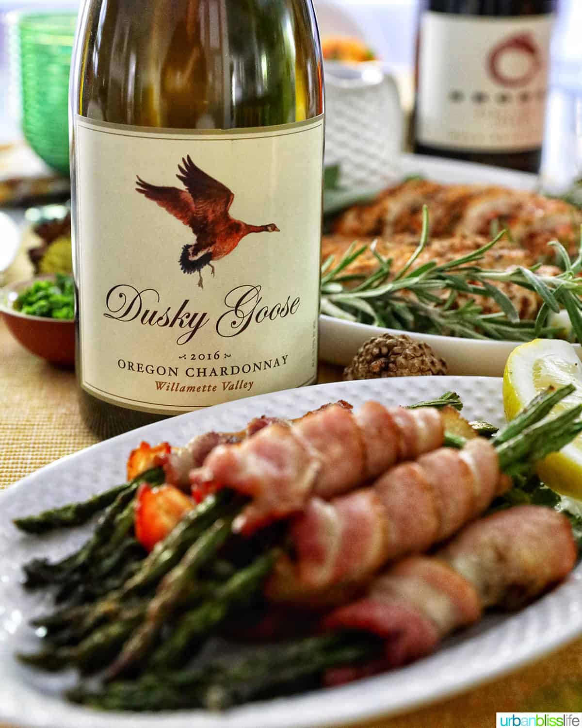 bacon wrapped asparagus on a white plate with a bottle of Oregon Chardonnay.