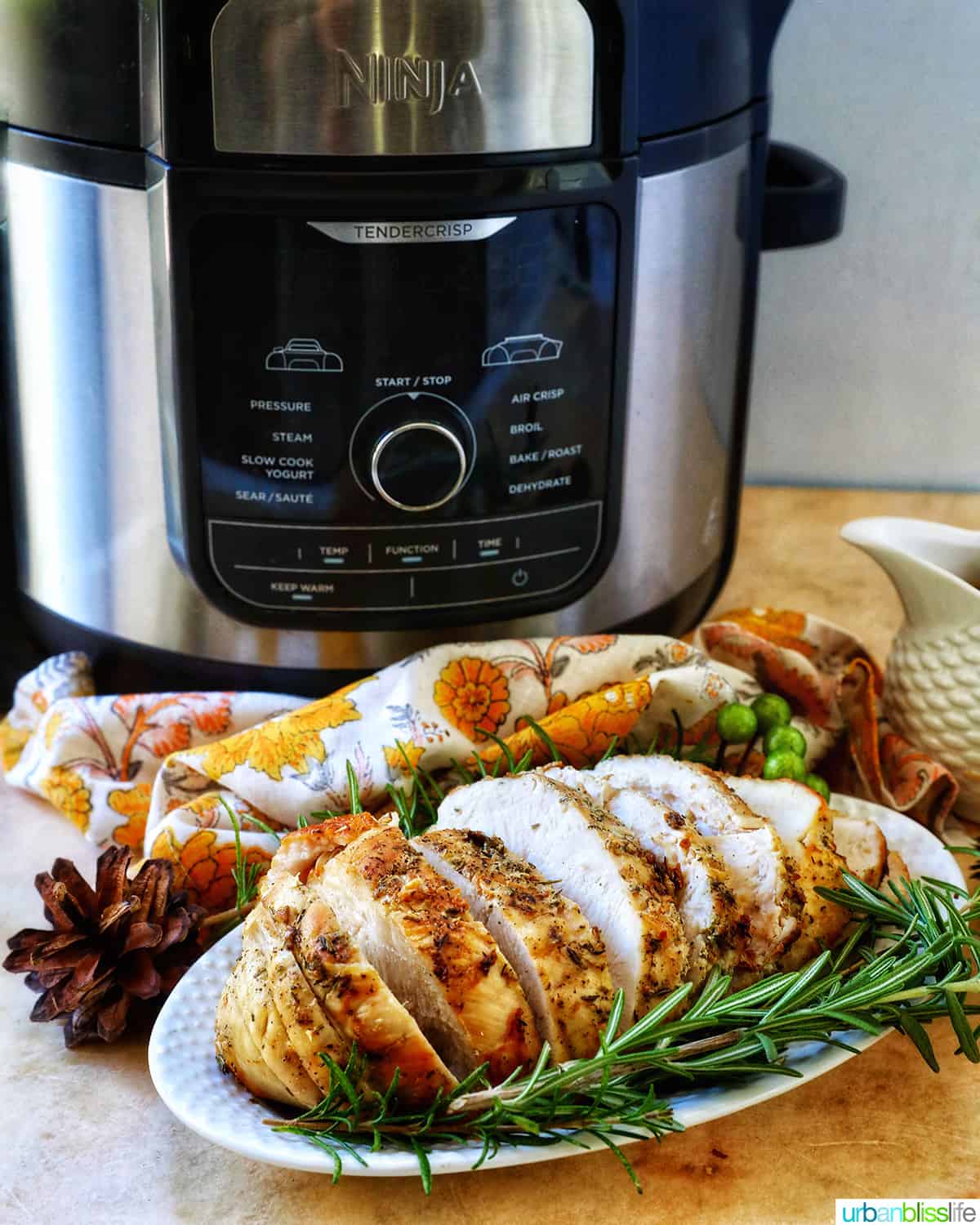 sliced air fryer turkey breast with herbs in front of an air fryer.