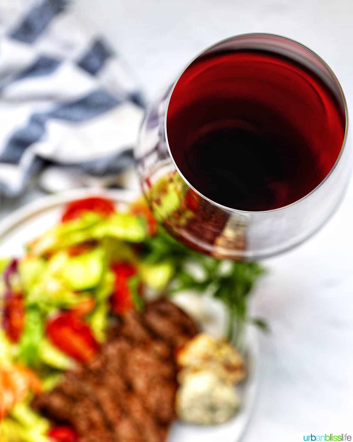glass of red wine with steak and salad.